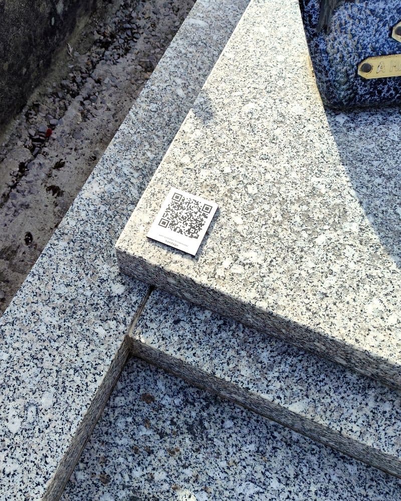 La plaque et son QR code, posée sur le rebord en granit d’une tombe.